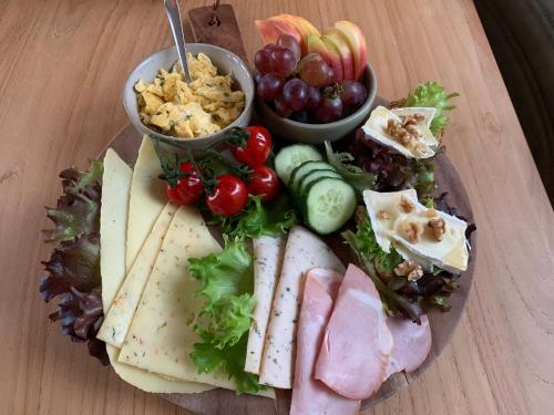 a plate of food with different types of cheese and fruit at De Logeerkamer Gapinge in Gapinge