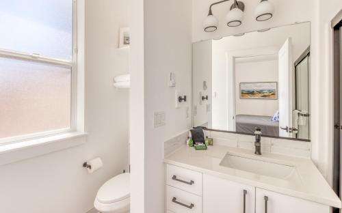 a white bathroom with a sink and a mirror at Harbor Lights 2 Family Fun Retreat Coastal Comfort in Depoe Bay