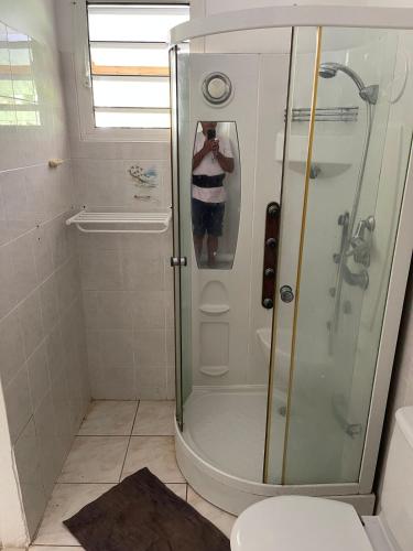 a man taking a picture of a shower in a bathroom at Le Pavillon Ananas in Gros-Morne