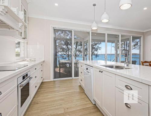 a kitchen with white cabinets and a view of the ocean at The Lakehouse Retreat in Summerland Point