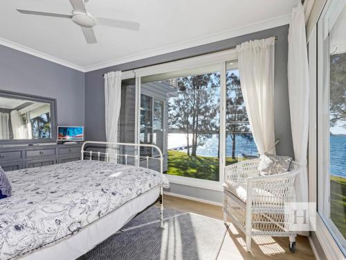a bedroom with a bed and a large window at The Lakehouse Retreat in Summerland Point