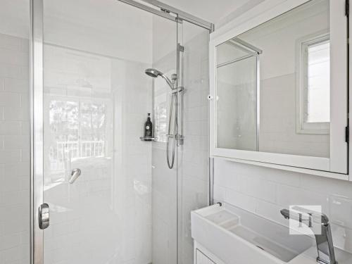 a white bathroom with a shower and a sink at The Lakehouse Retreat in Summerland Point