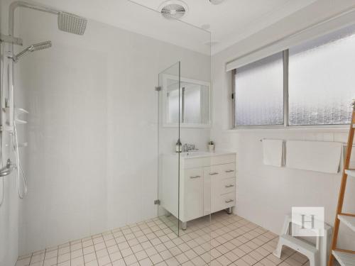 a white bathroom with a shower and a sink at Sunrise Wyong River in Wyong