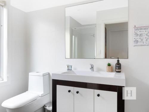 a white bathroom with a sink and a mirror at Sunset Central Coast in Mannering Park