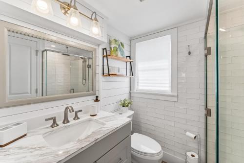 a white bathroom with a sink and a toilet at Boating Enthusiasts, Walk to the Beach, Heated Pool - The Corner cottage - Roelens in Fort Myers Beach