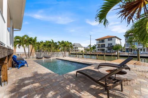 a swimming pool with two chairs next to a building at Boating Enthusiasts, Walk to the Beach, Heated Pool - The Corner cottage - Roelens in Fort Myers Beach