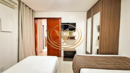 a hotel room with two beds and a mirror at Coruja Imob - Flat Crystal Place in Goiânia