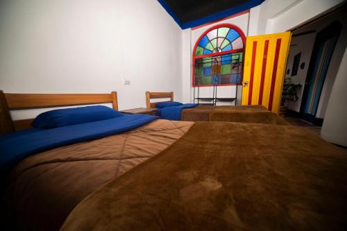 two beds in a bedroom with a stained glass window at Casa Tsao in Bogotá