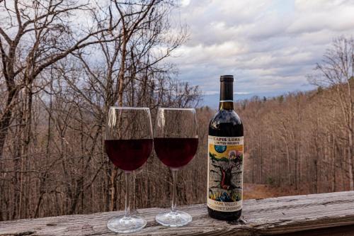 two glasses of red wine sitting on a wooden table at Whiskey Run Cabin, Spectacular Mountain Views in Bryson City