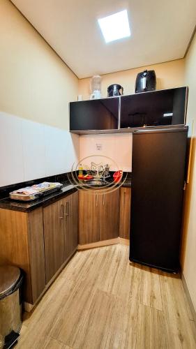 a kitchen with a black refrigerator and wooden cabinets at Coruja Imob - Flat Crystal Place in Goiânia