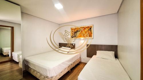 a room with two beds and a mirror at Coruja Imob - Flat Crystal Place in Goiânia