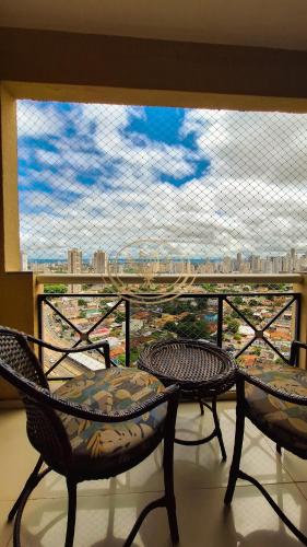 a balcony with two chairs and a large window at Coruja Imob - Flat Crystal Place in Goiânia