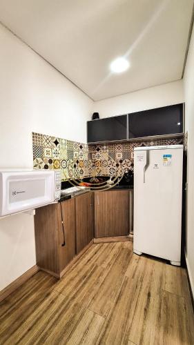 a kitchen with a refrigerator and a microwave at Coruja Imob - Flat Crystal Place in Goiânia