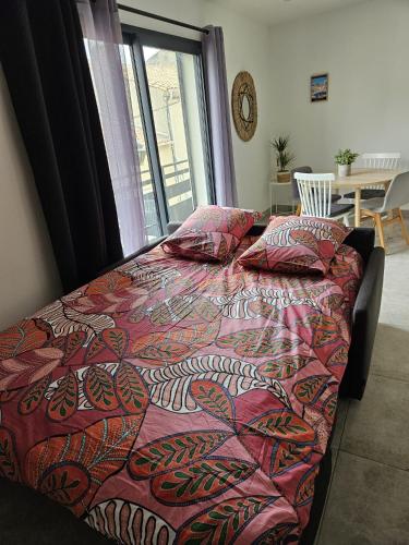 - un lit avec une couette et des oreillers colorés dans une chambre dans l'établissement 200m de la plage en centre ville au calme, au Grau-du-Roi
