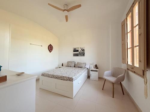 a white bedroom with a bed and a chair at Mas Nadal Montseny in Sant Esteve de Palautordera