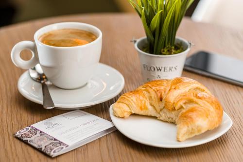 a table with a cup of coffee and a croissant at Hotel Moments Budapest by Continental Group in Budapest