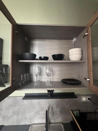 - une cuisine avec 2 verres à vin et des bols sur les étagères dans l'établissement Évasion Urbaine, Vue sur la ville, à Lons-le-Saunier