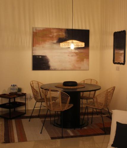 a table and chairs in a room with a painting at Boho Style Cozy 1 BHK Apartment in Abu Dhabi