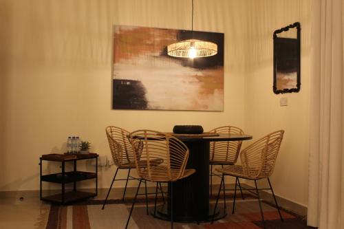 a table and chairs in a room with a painting at Boho Style Cozy 1 BHK Apartment in Abu Dhabi