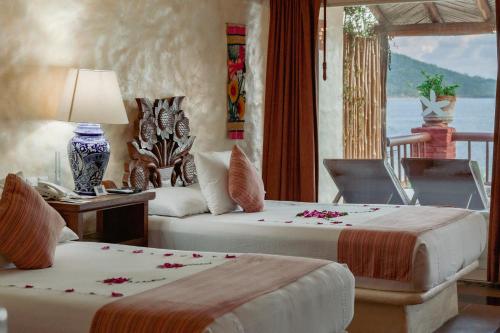 a bedroom with two beds and a table with a lamp at Hotel Aura del Mar in Zihuatanejo