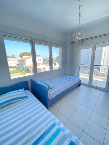 a bedroom with two beds and a couch and windows at Olivia sea side house in Hanioti