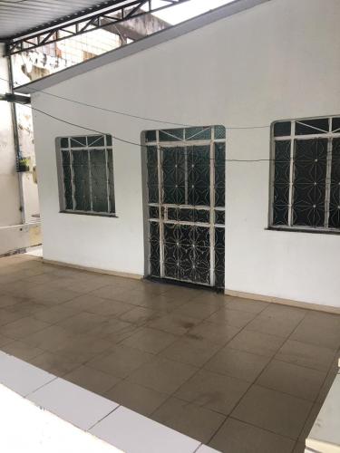 a white building with three windows and a tiled floor at Casa Aconchegante na praça 14 in Manaus