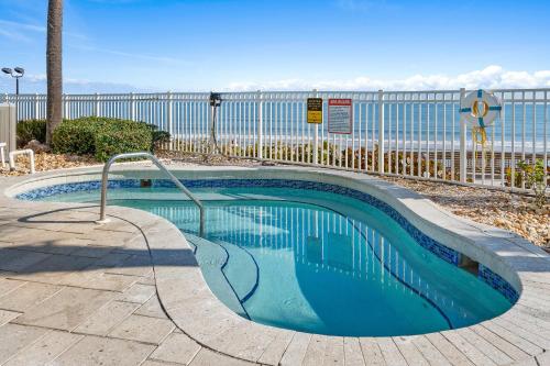 a swimming pool next to the ocean with a fence at 10th Floor Oasis Stunning 2BR with Spacious Private Double Balcony at The Wyndahm Ocean Walk Resort in Daytona Beach