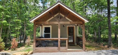 a tiny house with a porch in the woods at Menlo GA Tiny Home Experience in Rising Fawn
