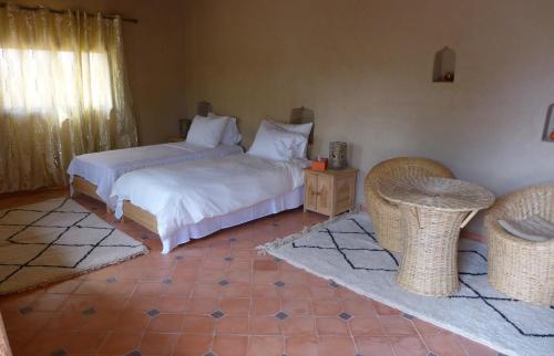 a bedroom with two beds and two wicker chairs at Les Jardins de la Santé in Tamazouzte