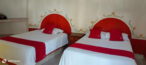 two beds in a room with red and white at Hotel San Jose Purua in Vidalrstn