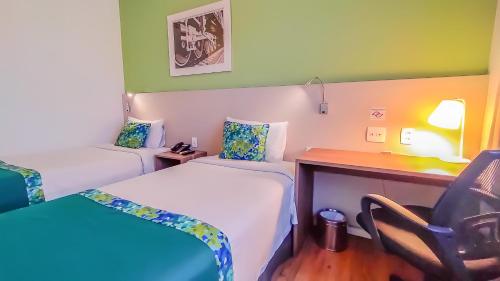 a hotel room with two beds and a desk at Blue Tree Towers Valinhos in Valinhos