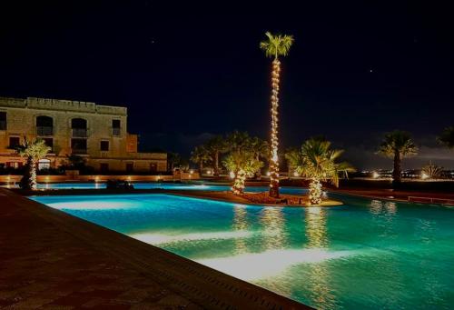 a swimming pool with a palm tree at night at Fort Chambray, Blissful Escape in Għajnsielem