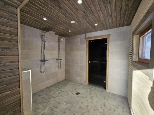 Un baño con ducha a ras de suelo y lavabo. en Villa Tuliniemi, en Siilinjärvi