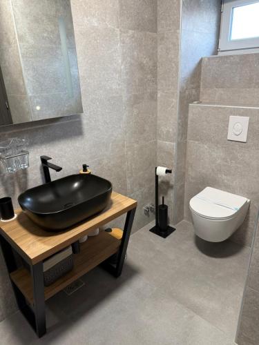 a bathroom with a black sink and a toilet at Dalma Pro Apartments - Cozy Studio & Spacious One-Bedroom Apartment - Self Check-in in Karlovac