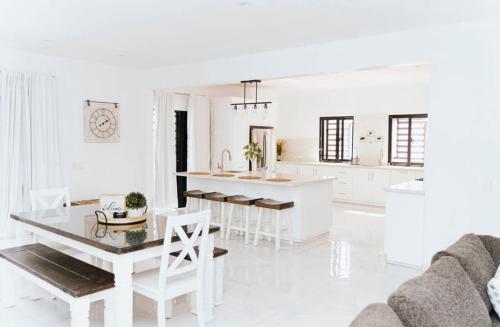 a white living room with a table and a kitchen at The Jhonson villa con piscina en Las Galeras in Las Galeras