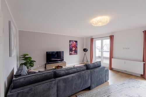 a living room with a large couch and a tv at UNiQE I Luxuriöses 145qm Apartment in Feldafing