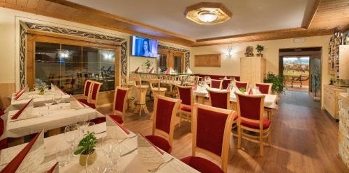 a restaurant with white tables and red chairs at Hotel Duc De Rohan in Livigno
