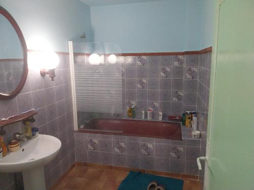 La salle de bains est pourvue d'une baignoire rouge et d'un lavabo. dans l'établissement jolie maison charentaise, à Marennes