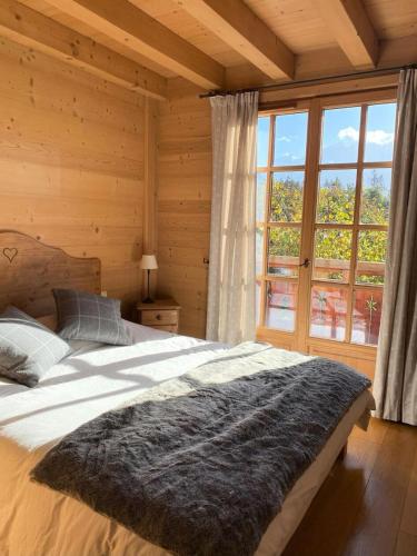 une chambre avec un grand lit et une grande fenêtre dans l'établissement Chalet Medonnet - CHALET 10 personnes Combloux MAE-7241, à Combloux