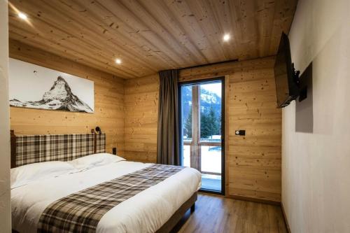 une chambre avec un lit et une grande fenêtre dans l'établissement Chalet Le Cervin - Chalet en triplex 14 personnes 5 exposé Sud-Est MAE-7551, à Valloire