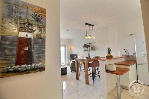 a kitchen and living room with a lighthouse painting on the wall at Ker gwelanig in Trégastel