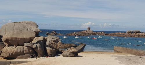 a beach with rocks and boats in the water at Ker gwelanig in Trégastel