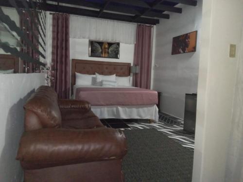 a hotel room with a bed and a leather couch at Sky Beach Hotel in Hopewell