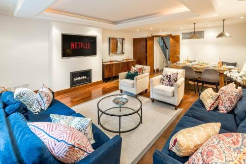 a living room with blue couches and a dining room at -Air con- Luxury Townhouse - High St Kensington! in London
