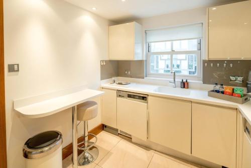 a kitchen with white cabinets and a sink and a window at -Air con- Luxury Townhouse - High St Kensington! in London