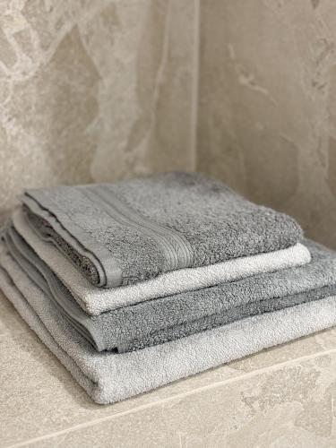 - une pile de serviettes assises sur un comptoir dans la salle de bains dans l'établissement Appartement de luxe climatisé, parking & 2 balcons, à Villefranche-sur-Mer