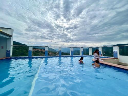 a woman and two children in a swimming pool at 1004AptoPoolTurkishSaunagood location in San Gil