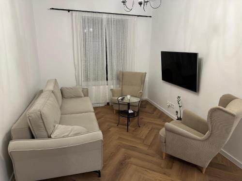 a living room with a couch and two chairs and a tv at Apartament Św Ducha Starówka in Elblag