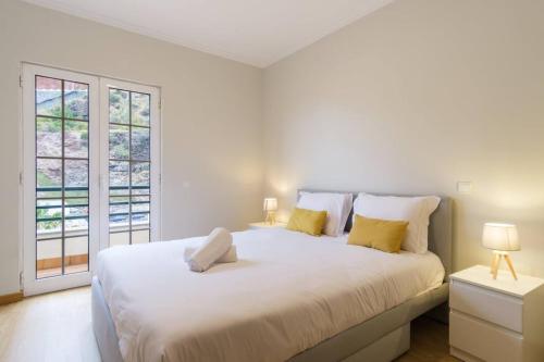 1 dormitorio blanco con 1 cama grande con almohadas amarillas en Brava Home - Best Location to Explore Madeira, en Ribeira Brava