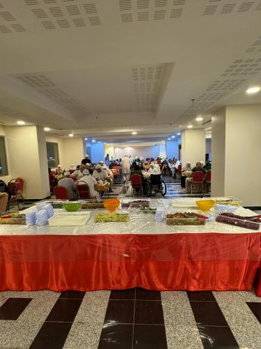 Eine Gruppe von Menschen sitzt in einem Raum an einem Tisch mit Essen. in der Unterkunft فندق نوم وسكون in An Nikāshah